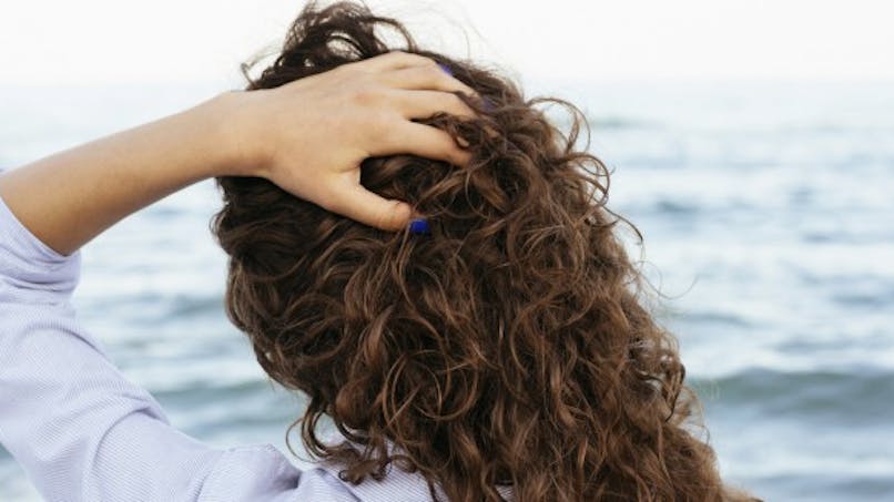 Une femme se caresse les cheveux à la plage