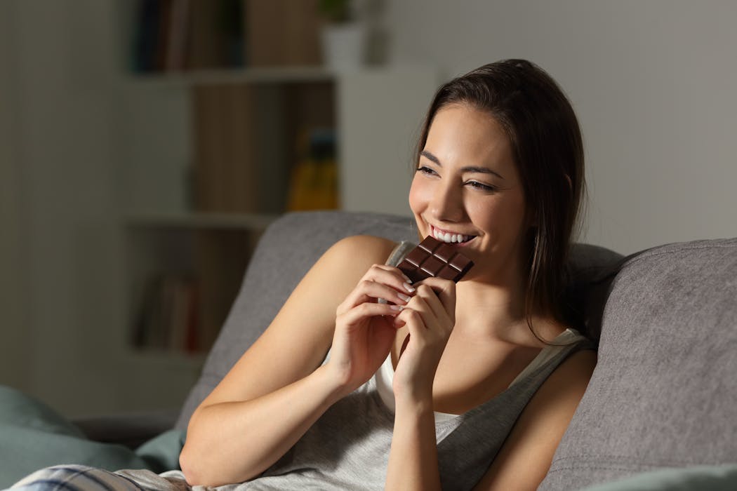 Prepara un bocadillo mujer joven comiendo barra de chocolate