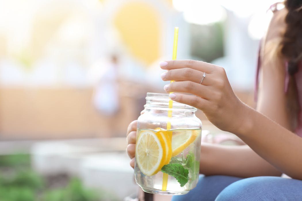 Mantente hidratado con agua Mujer joven, con un tarro de limonada fresca