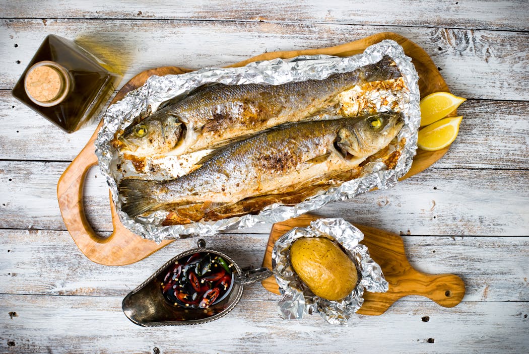 Apostar por los métodos de preparación adecuados Lubina fresca, pescado al horno, cocinado en papillote