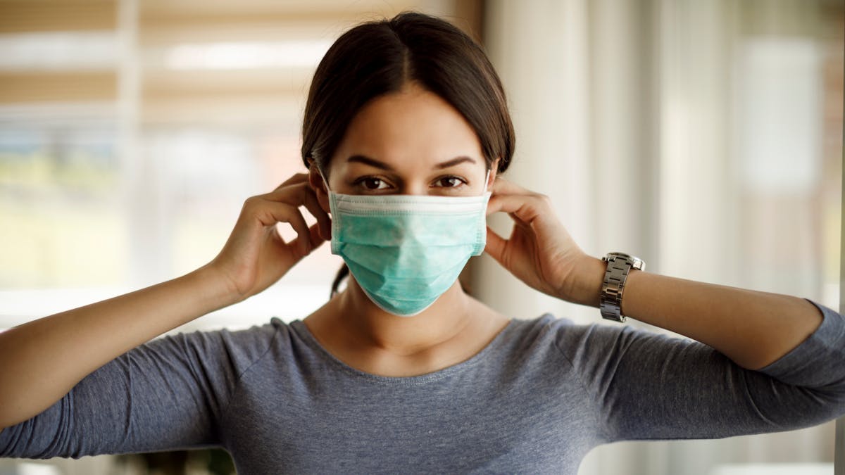Une femme porte un masque de protection jetable contre le coronavirus.