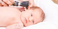 Médecin contrôlant l'oreille d'un bébé à l'aide d'un otoscope.