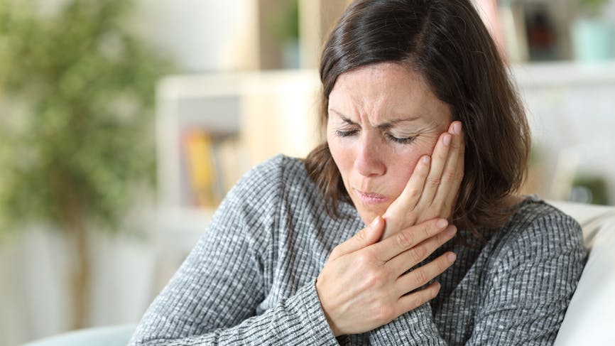 Une femme souffre de gingivite et se tient la mâchoire