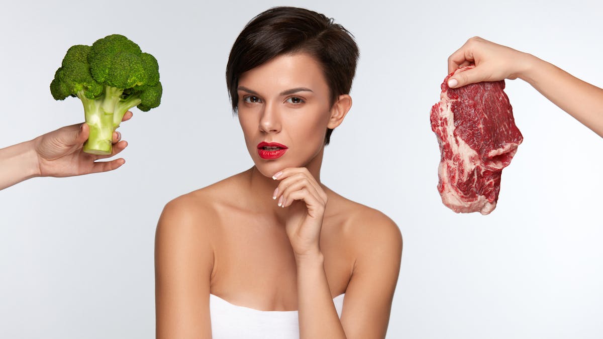 femme hésitant entre viande et légume