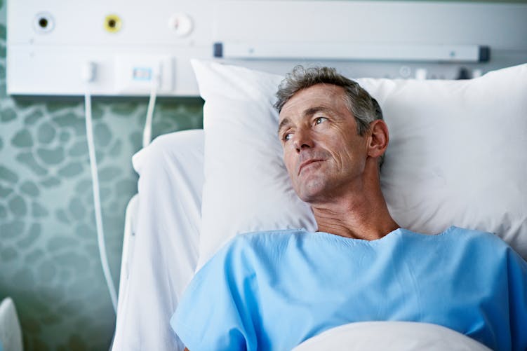Un homme sur un lit d'hôpital attend son opération