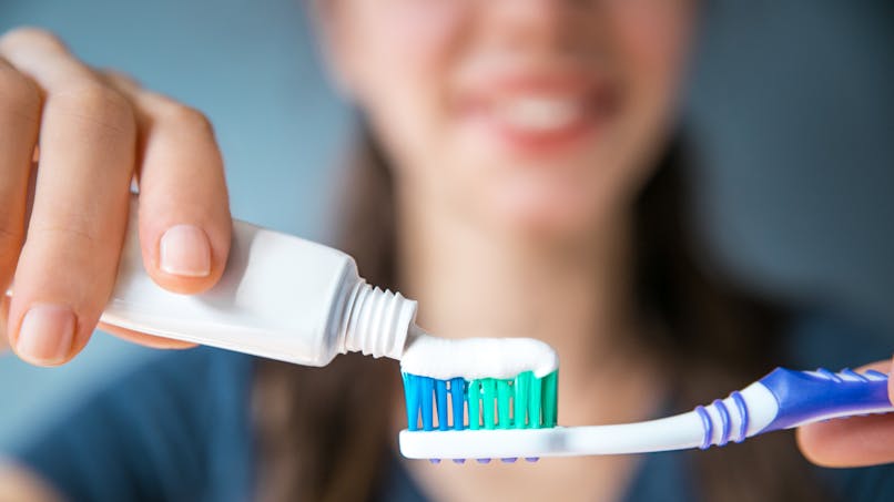 femme-mettant-du-dentifrice-sur-une-brosse-a-dents