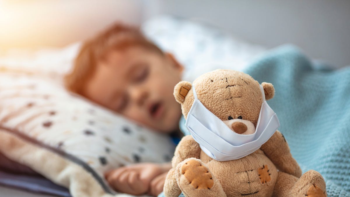 Bébé qui dort avec son ours en peluche masqué