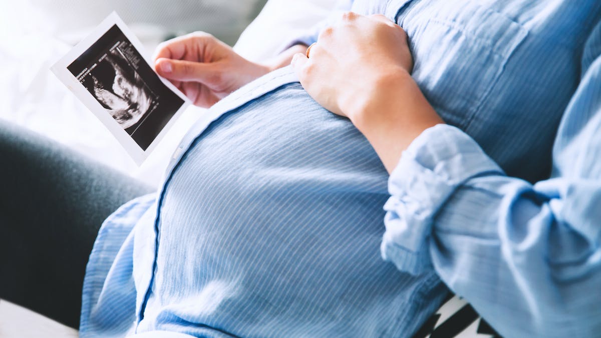 Une femme enceinte tient une échographie dans sa main