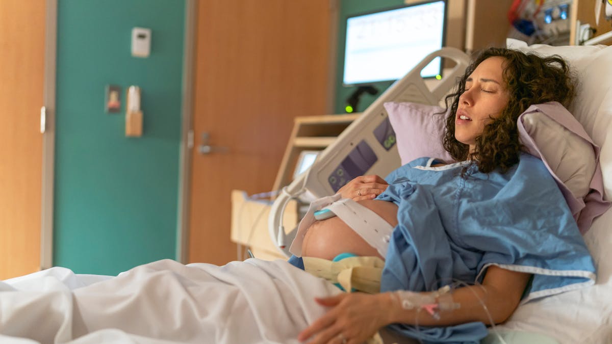 Femme enceinte avec monitoring sur un lit d'hôpital.