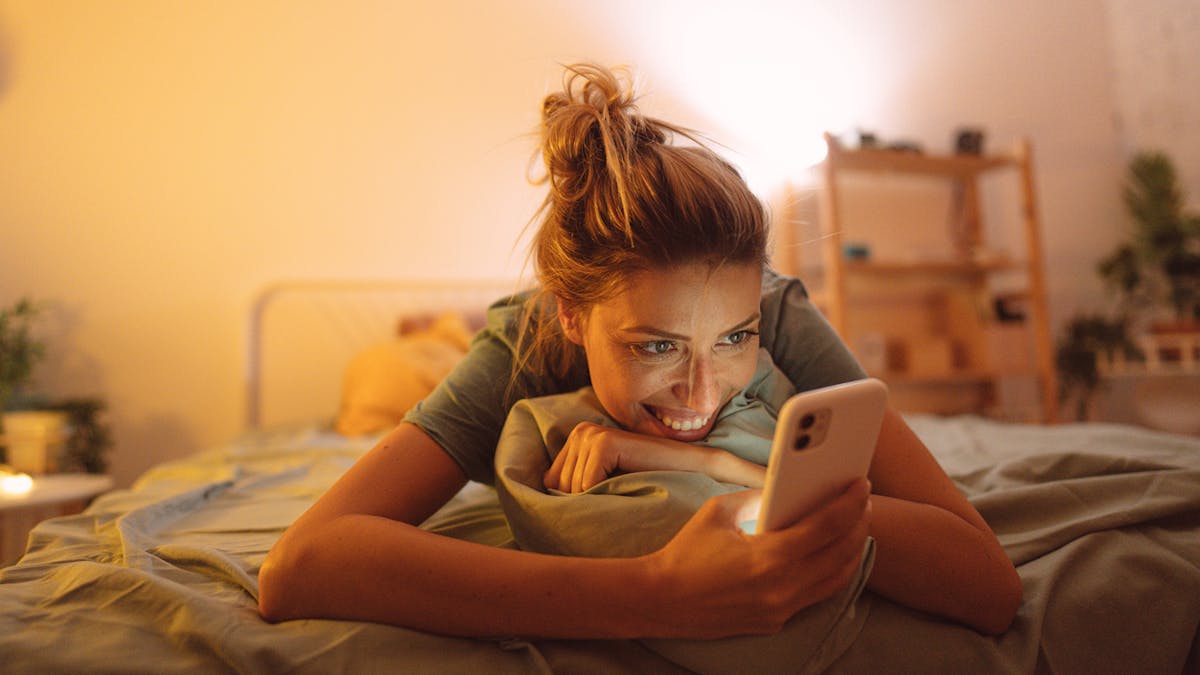 Groundhogging : une jeune femme consulte son portable au lit