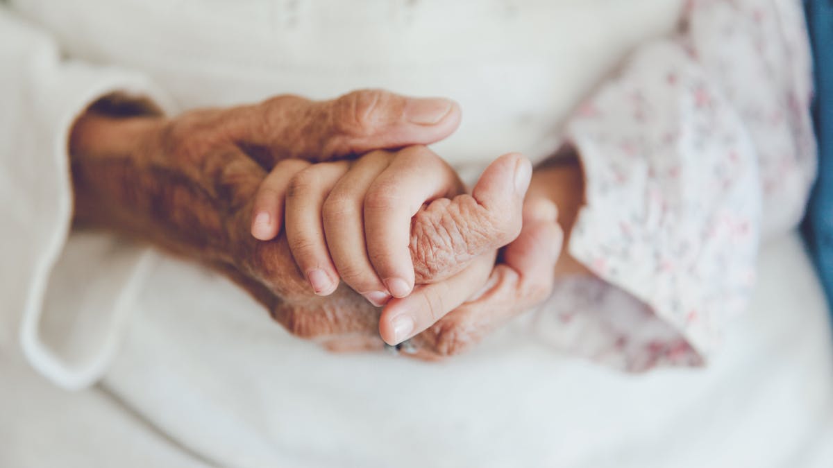 Femme âgée tient la main de sa petite-fille