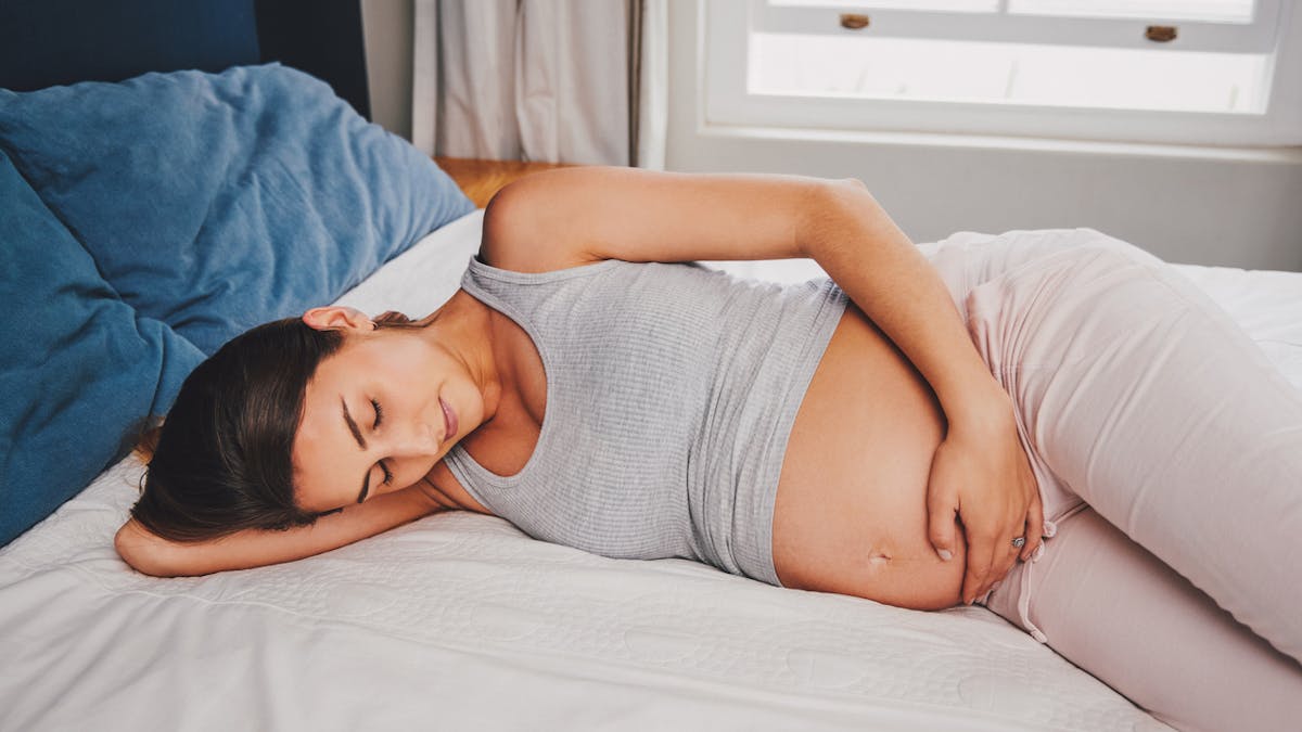 Femme enceinte allongée sur un lit.