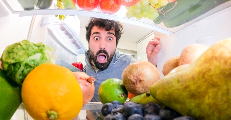 Un jeune homme ouvre son frigo et a peur des fruits qui s'y trouvent (carpophobie)
