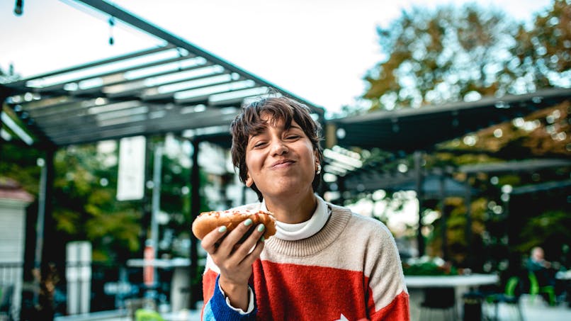 Une jeune femme mange un hot-dog