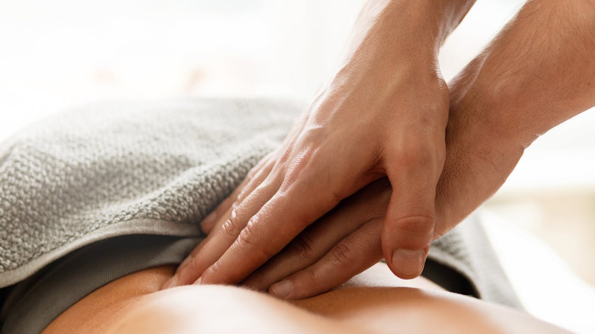 Une femme réalise un massage des lombaires