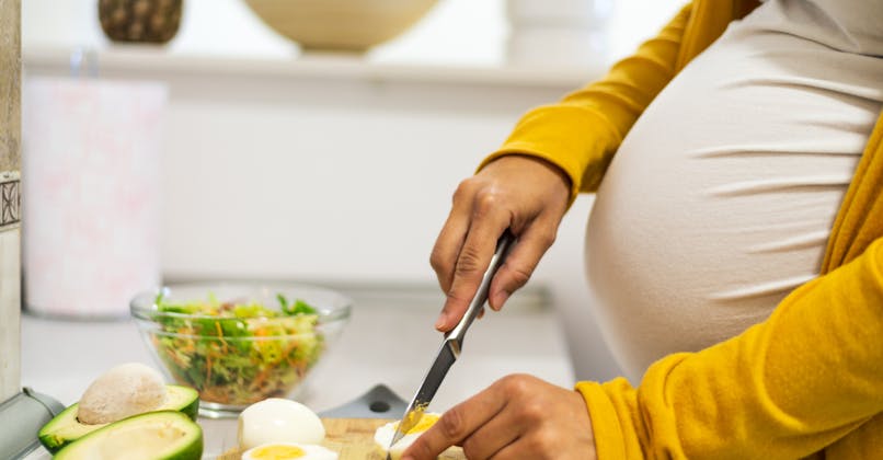 Une femme enceinte coupe un œuf
