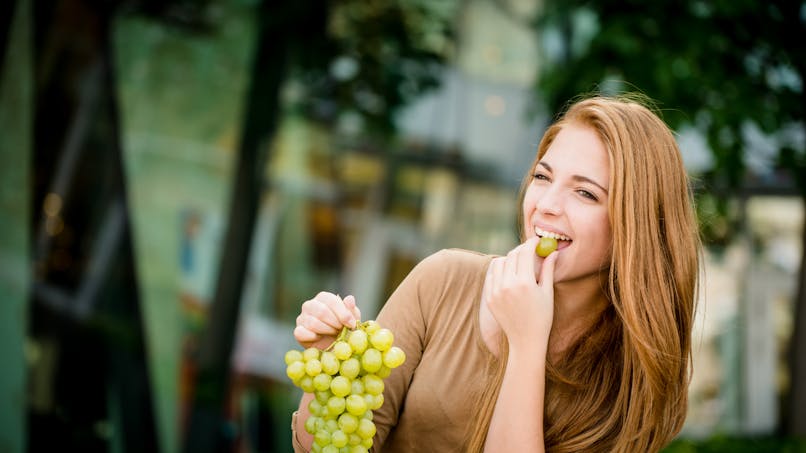 Une femme mange du raisin