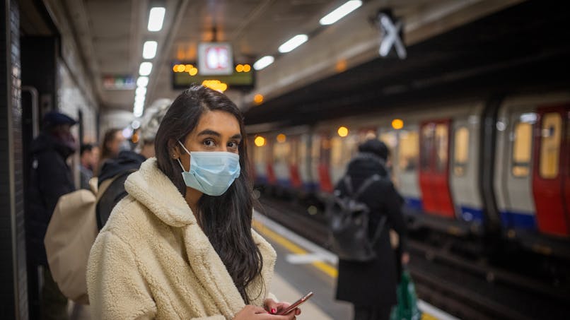 Une jeune femme porte un masque dans le métro