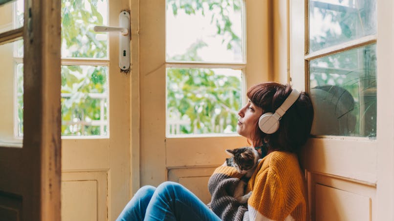 Une jeune femme regard par la fenêtre avec son chaton