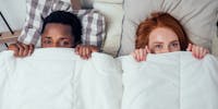 Un couple au lit se cache sous sa couette