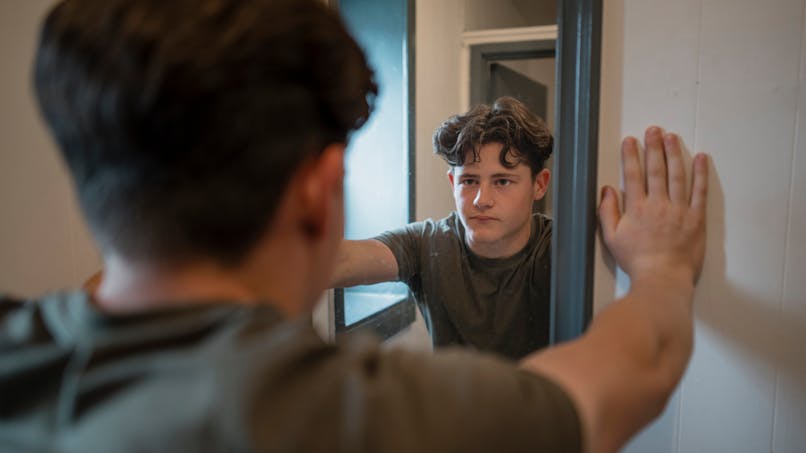Un adolescent se regarde dans un miroir