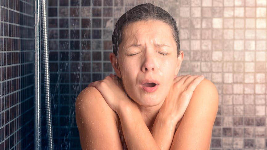 Femme nue réagir en prenant une douche froide