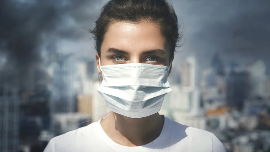 Femme portant le masque facial en raison de la pollution de l’air dans la ville