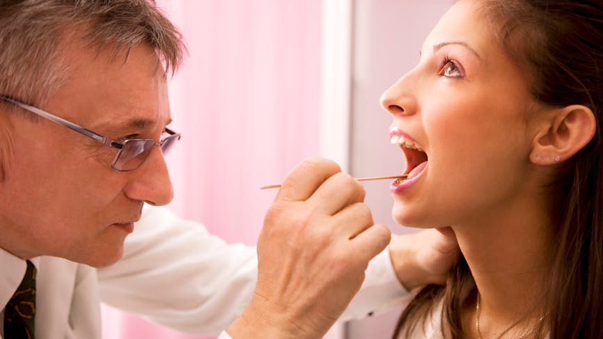 Médecin examinant la langue d'une jeune femme avec un abaisse-langue