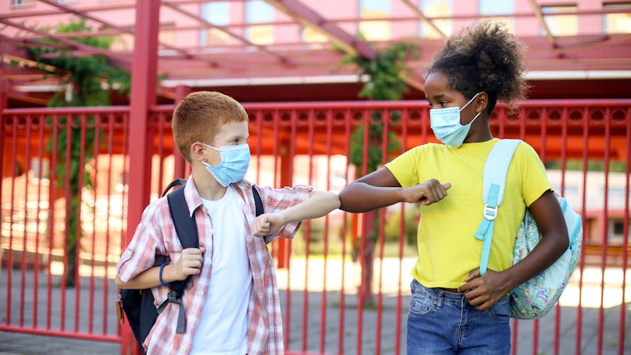 Deux enfants dans une cour d'école pendant la pandémie du coronavirus. Tous deux âgés d'environ 10 ans, ils portent le masque. 