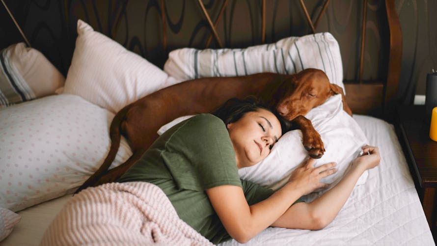 Une jeune femme dort avec son chien