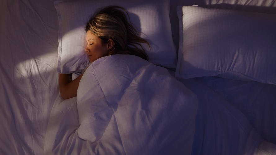 femme qui dort paisiblement dans un lit confortable et spacieux aux draps blancs