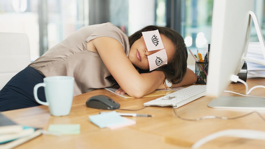 Photo d'une femme d'affaires fatiguée faisant une sieste à son bureau avec des post it sur les yeux 