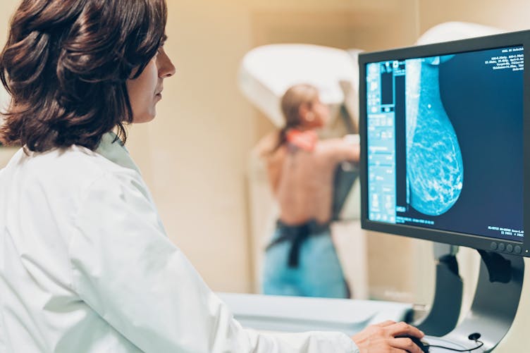 Une femme en train de réaliser une mammographie.