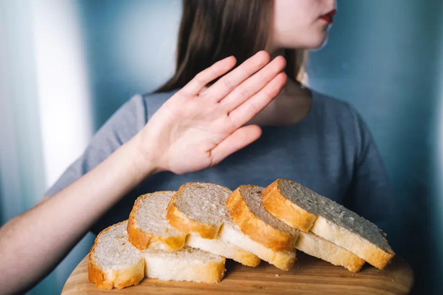 Personne refusant du pain avec un geste de la main, symbolisant une restriction alimentaire.
